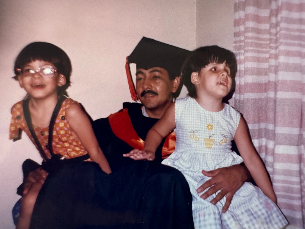 Graduación del padre de las hermanas mientras tiene en su regazo a Laura Andrea y María Paula.