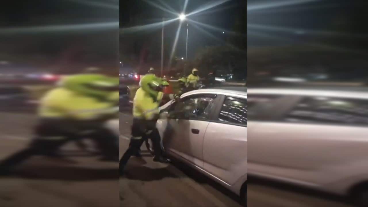 Policía rompe con un bolillo el vidrio del carro de un conductor de Uber