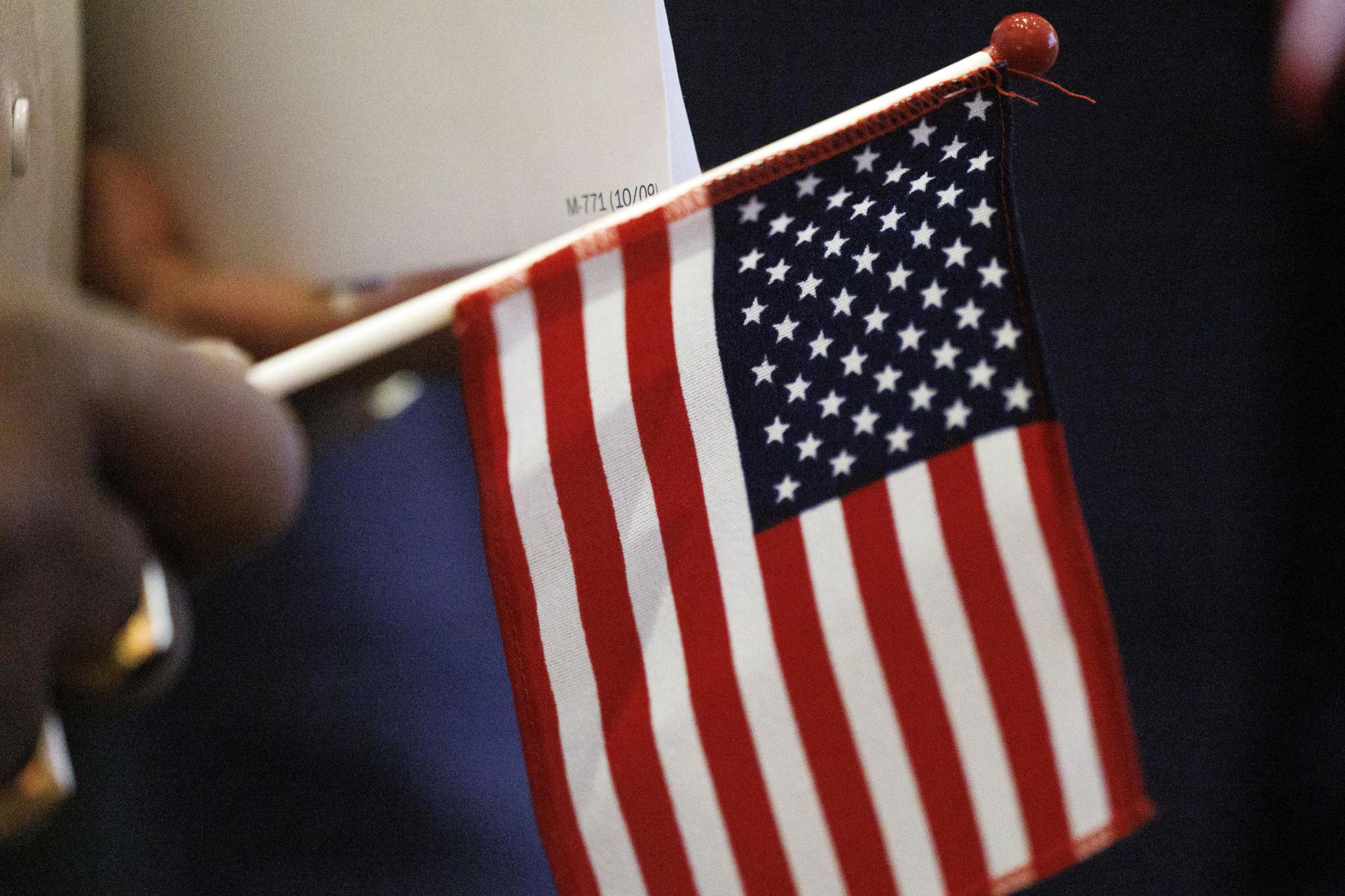 Una persona sostiene una pequeña bandera de Estados Unidos.